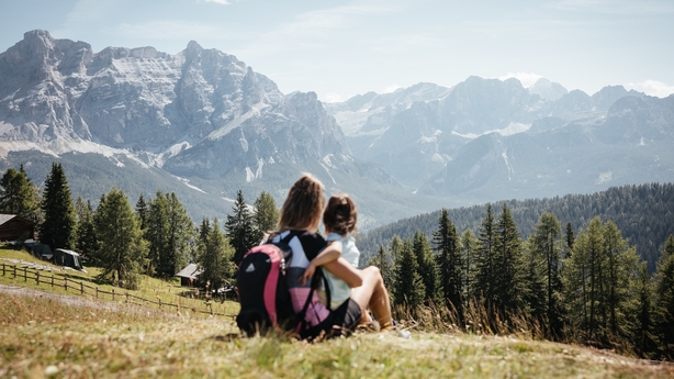 a person and child sitting on a hill looking at mountains