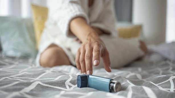 Girl suffering asthma attack reaching inhaler sitting on a bed in the bedroom at home. Woman Hand Reaching Inhaler Because She Suffering From Asthma Attack 