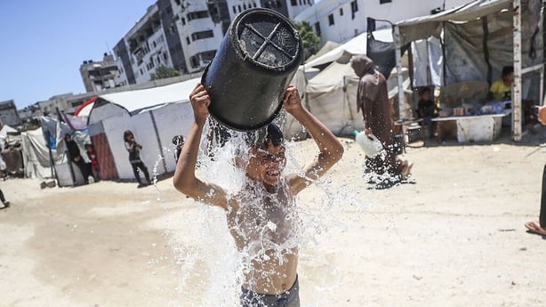 GAZA CITY, GAZA - JULY 07: A child cools off with water as an aid truck distributes water to displaced Palestinians in Gaza City, Gaza, where residents carry the supplies in plastic jerrycans amid a worsening water crisis, on July 7, 2025. Israeli attacks have severely damaged the city's infrastruct