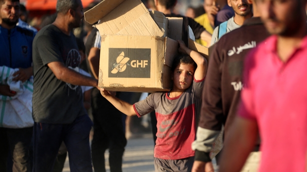 A young boy carrying an aid parcel, walks along the Salah al-Din road near the Nusseirat refugee camp in Gaza
