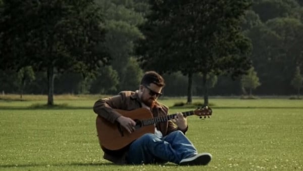 a person sitting on the ground playing guitar