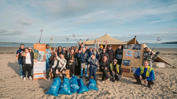 a group of people posing for a photo on a beach after cleaning up the area