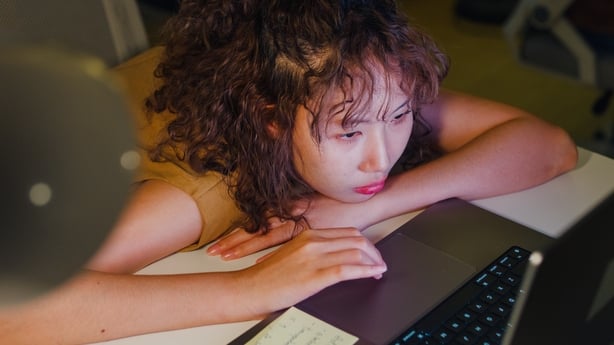 Closeup of exhausted young Asian woman working on her laptop
