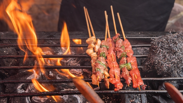 skewers on a grill with flames on it