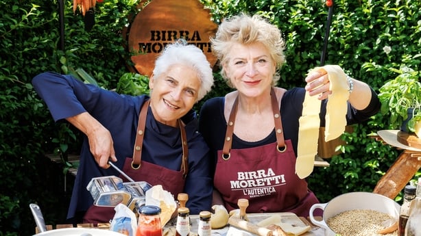 two women in aprons holding food