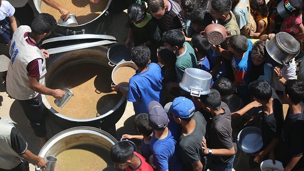 Palestinians, including many children gather to receive food aid distributed by a charity organization