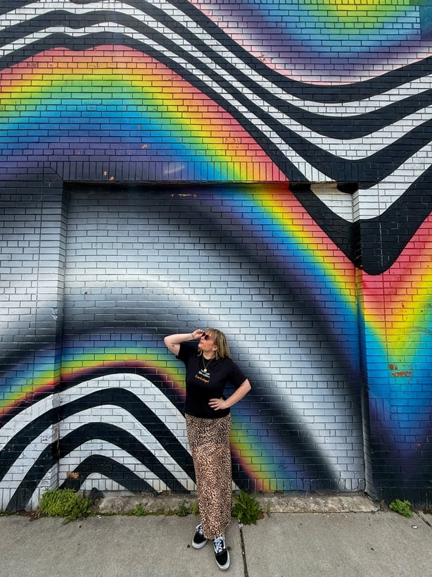 a person standing in front of a multicoloured mural