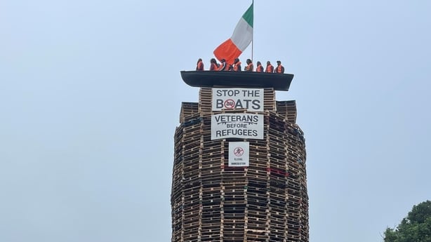 A tricolor flag and a migrant boat effigy can be seen on top of a bonfire in Co Tyrone