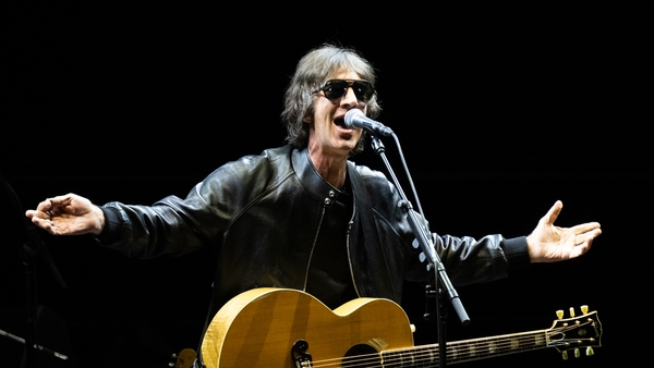 a person singing into a microphone with his hands out