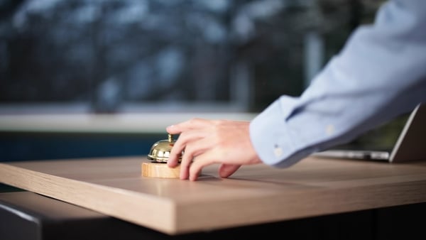 Hand pressing bell at hotel reception desk