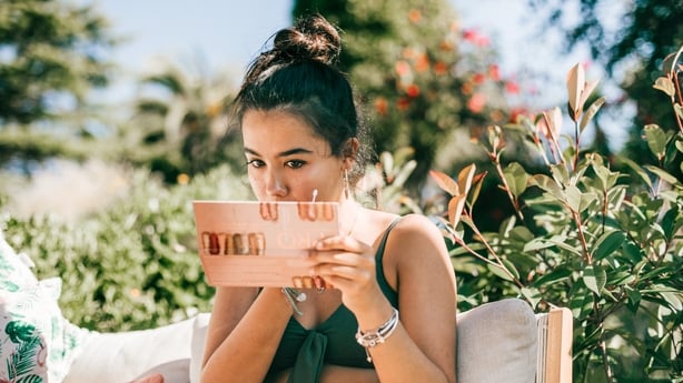 young woman applying makeup outdoors during summer holidays