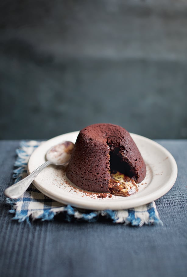 a small round white plate with a chocolate fondant dessert on it