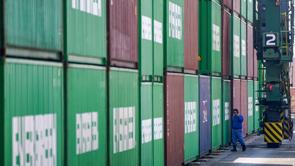 a person walking next to a stack of shipping containers