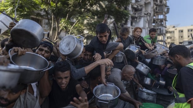 Palestinians, including children, try to get food distributed by a charity organisation in the Al-Rimal neighbourhood of Gaza City
