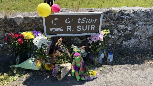 Flowers and balloons left at sign saying R. Suir