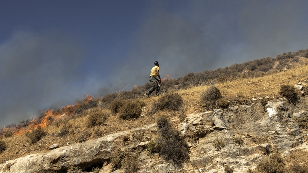 A Palestinian man runs across a hill on fire as he tries to chase off Israeli settlers in the village of Sinjil, in the occupied West Bank
