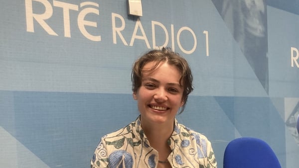 writer Mariam Tell, in radio studio for Sunday Miscellany, behind mic and turned to smile into camera