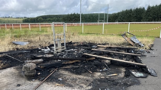 The smouldering remains of a shop and scoreboard following an arson attack on Lámh Dhreag GAA club in Co Antrim