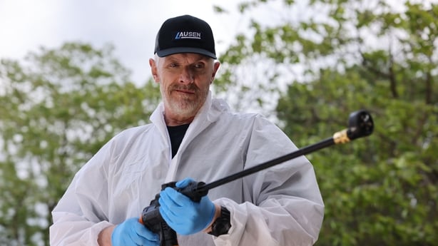 a person wearing gloves and a white coat holding a hose