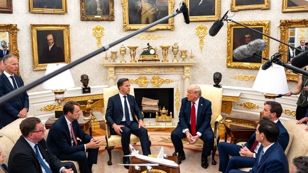 a group of men in suits sitting in a round room with a microphone