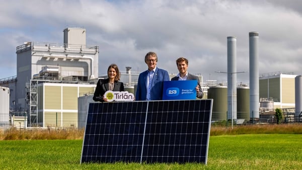 Managers from Tirlan and ESB in a field with a solar panel at Tirlan's facility in Co Kilkenny