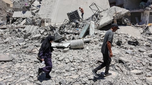 Palestinians walk on the rubble of buildings destroyed a day earlier by Israeli strikes on Al-Daraj neighbourhood in Gaza City