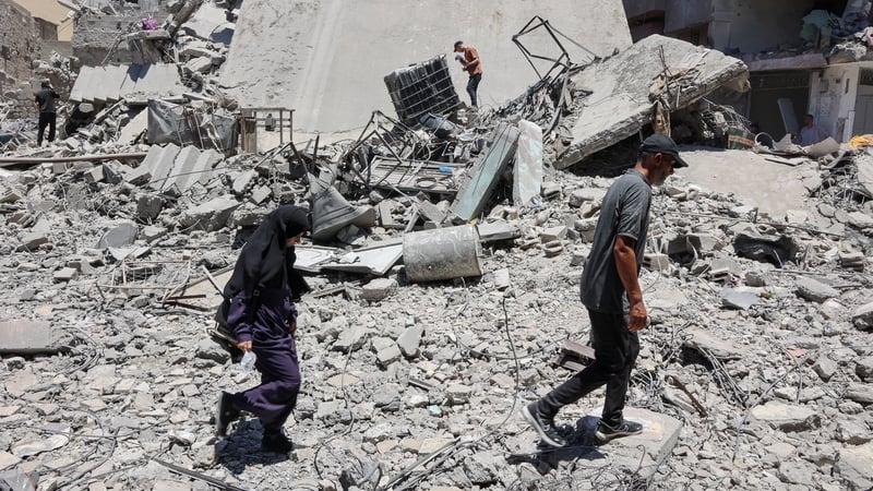 Palestinians walk on the rubble of buildings destroyed a day earlier by Israeli strikes on Al-Daraj neighbourhood in Gaza City