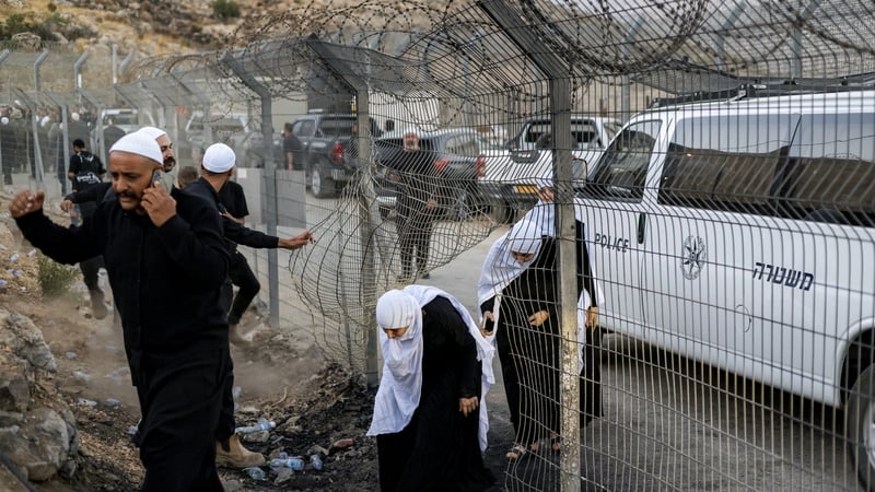 Members of the Druze community passing through a hole in a barbed-wire border fence in the Israeli-annexed Golan Heights