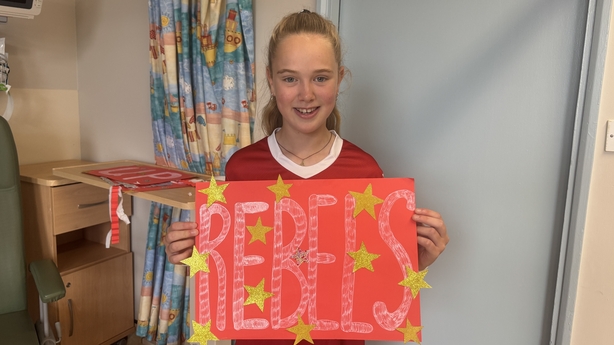 Anna Cronin holds a sign saying 'Rebels' in Cork University Hospital