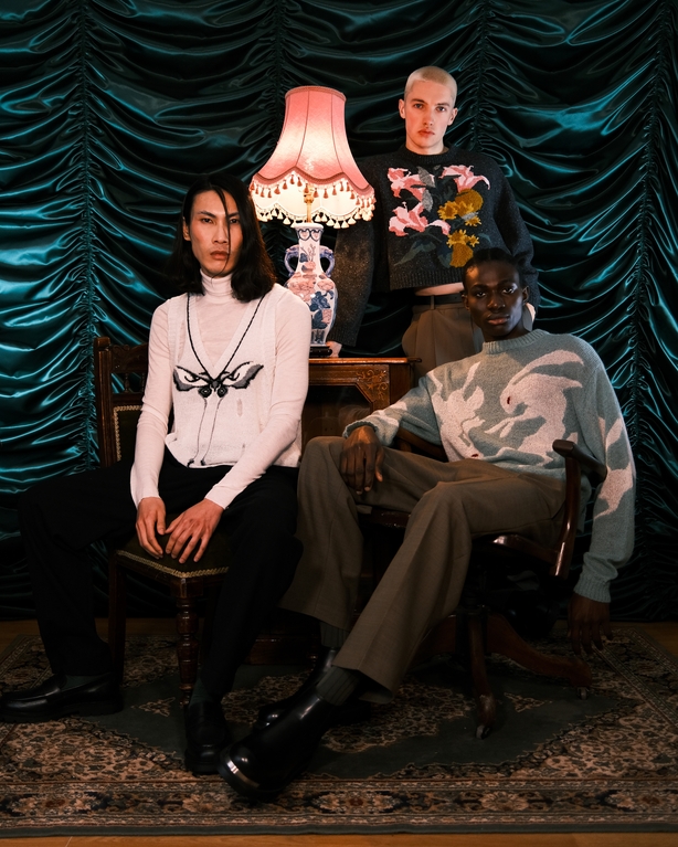 a group of people sitting in front of a curtain wearing Irish knitwear designs