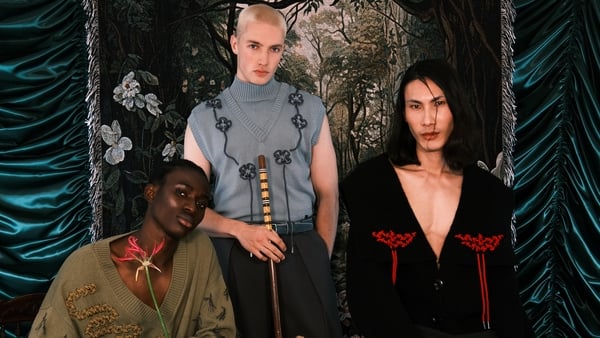 a group of people sitting in front of a curtain wearing Irish knitwear designs