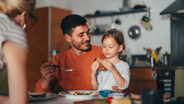 An adorable smiling Caucasian child having a meal together with her family.