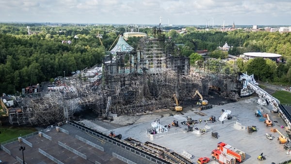 a building under construction with trees and a cloudy sky