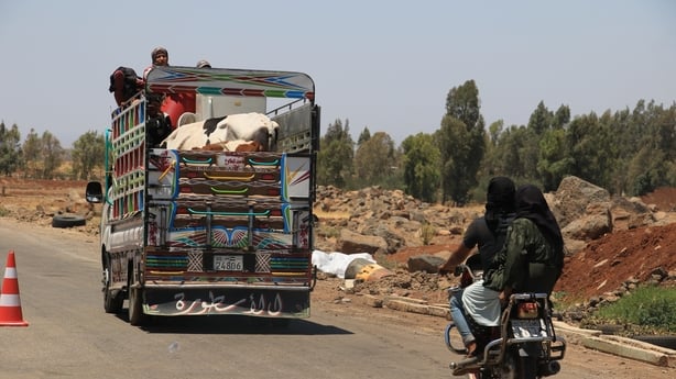 a truck and a motorcycle with people on board drive down a path 