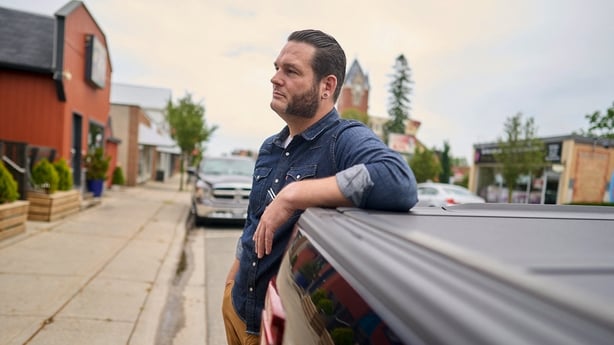 Brett Hueston, publisher of the Aylmer Express newspaper, leans up against his pickup truck in downtown Aylmer, Ontario , Canada