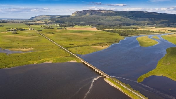 A scenic drone shot of a bridge over a river in Northern Ireland