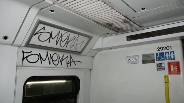 black text graffiti on a white wall of a train
