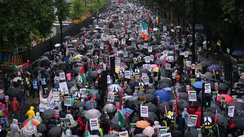 Pro-Palestinian supporters march with placards and umbrellas in the rain in central London