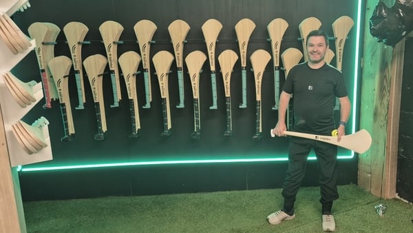 Sean Torpey stands with dozens of hurleys on the wall behind
