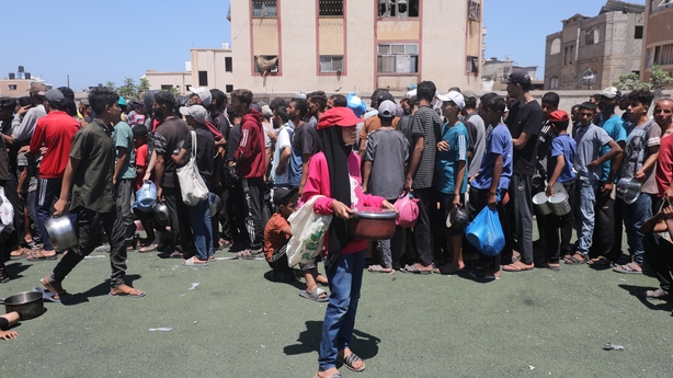 Palestinians wait to receive a hot meal in Gaza City