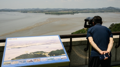 A tourist uses binoculars to watch the North Korean side of the DMZ dividing the two Koreas, from South Korea's Odusan Unification Observatory in Paju on 12 June