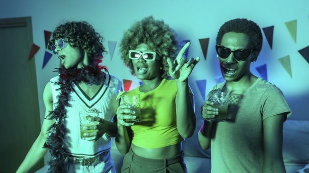 a group of people holding drinks dancing at a house party