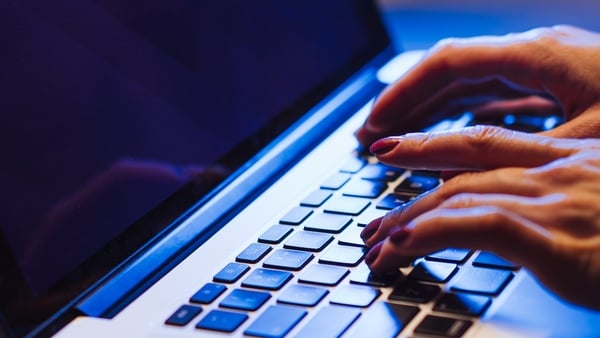 Woman typing on a laptop with a comfortable, cozy atmosphere and warm ambient lighting, embodying focus and creativity in a relaxed home environment.