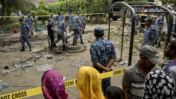 GETTY Onlookers gather as Bangladesh Air Force personnel recover debris while inspecting the crash site