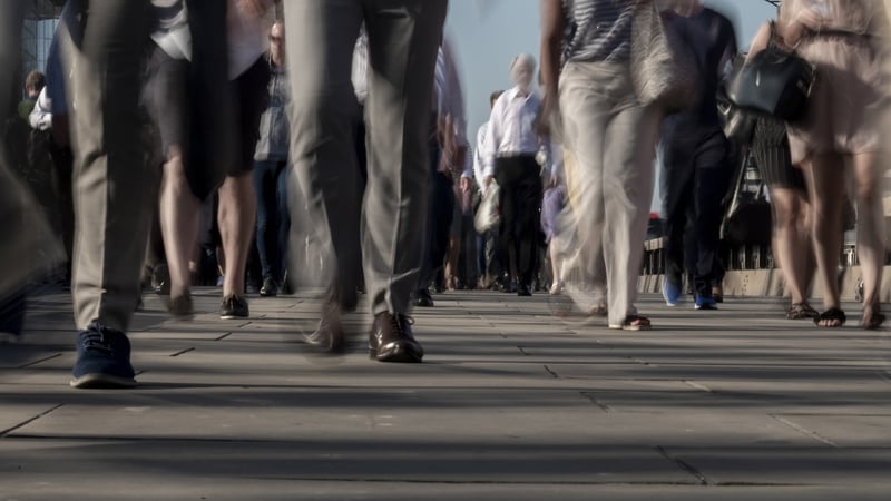 Stock image shows blurred photograph of many people walking on a street