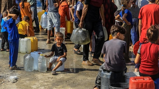 a group of people with water jugs and plastic bags