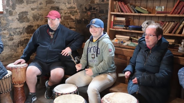 Three men posing for a photo during festival preparations as they play drums