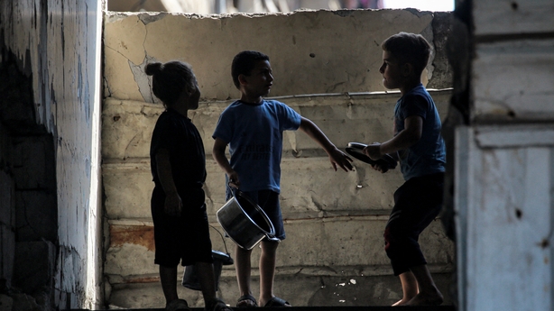 Children wait with pots to receive meals from a charity kitchen in Gaza