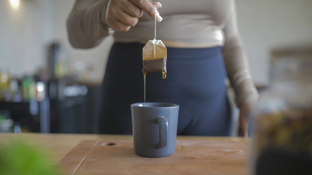 a person pouring a tea bag into a mug
