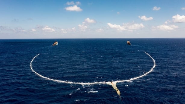Two boats in the ocean with a net trailing